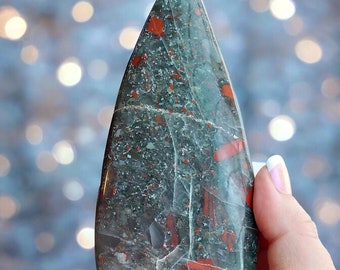May include: A green and red jasper point with a unique, swirling pattern. The point is polished and has a smooth, glossy finish.