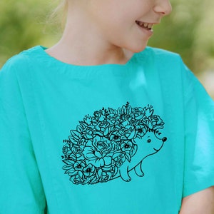 May include: A turquoise t-shirt with a black line drawing of a hedgehog covered in flowers.