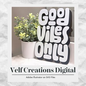 May include: White and black cutout letters spelling "Good Vibes Only" on a black background. The letters are in a playful, rounded font. The letters are sitting on a white surface in front of a potted plant.