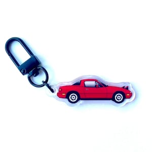 May include: A red car keychain with a black metal clip. The car is a red Mazda Miata.