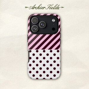 Op de afbeelding: Een smartphonehoesje met een gespleten ontwerp, voorzien van diagonale roze en donkerbruine strepen op de bovenste helft en een witte achtergrond met donkerbruine stippen op de onderste helft. De tekst Archier Fields staat boven het hoesje.
