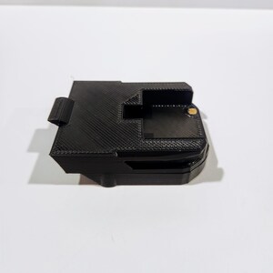 May include: Black plastic battery holder with a textured surface and a small gold screw.