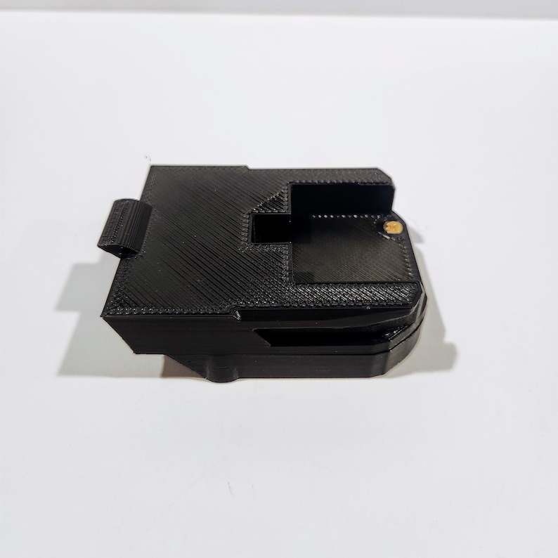May include: Black plastic battery holder with a textured surface and a small gold screw.
