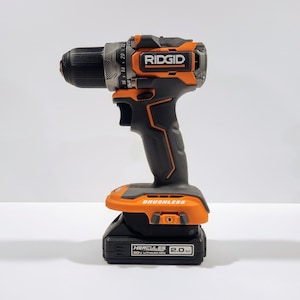May include: An orange and black cordless drill with a brushless motor and a 20V lithium-ion battery. The drill has a black handle and a black and orange trigger. The battery is labeled "Hercules 2.0 Ah".