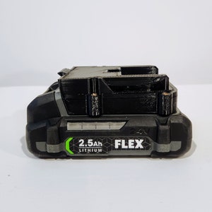 Puede incluir: Una bater&iacute;a de herramienta el&eacute;ctrica negra y gris con una etiqueta verde que dice "2.5Ah Lithium FLEX 24V".