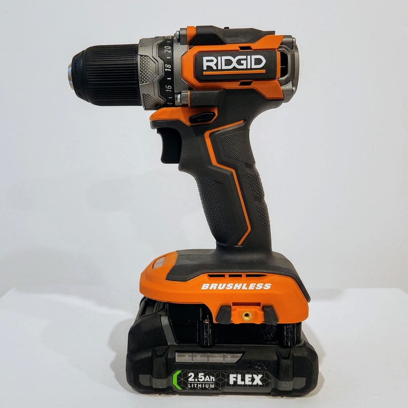 Puede incluir: Un taladro inal&aacute;mbrico naranja y negro con motor sin escobillas y una bater&iacute;a de litio de 2,5 Ah. El taladro est&aacute; hecho por RIDGID y tiene un logotipo "FLEX" en la bater&iacute;a.