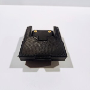 May include: A black 3D printed plastic mount with two gold screws.