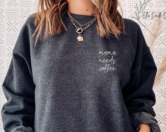 May include: A dark gray sweatshirt with the text "mama needs coffee" in white lettering on the front.