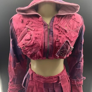 May include: A pink and purple tie-dye denim jacket and skirt set with a zipper closure and distressed details. The jacket has a hood and the skirt is pleated.