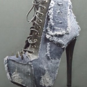 May include: A pair of high-heeled boots with a denim upper. The boots have a pointed toe and a stiletto heel. The denim is distressed and has a patchwork design. The boots are decorated with silver studs.