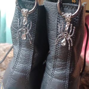 May include: Black leather boots with a yellow and black tag that says "Dr. Martens" and "Air Wair" on the back.  Each boot has a silver spider charm attached to a silver ring.