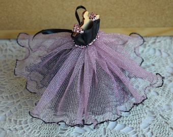 May include: A black and pink tulle dress with a black bodice and pink tulle skirt. The dress is decorated with small pink beads and has a black ribbon around the waist.