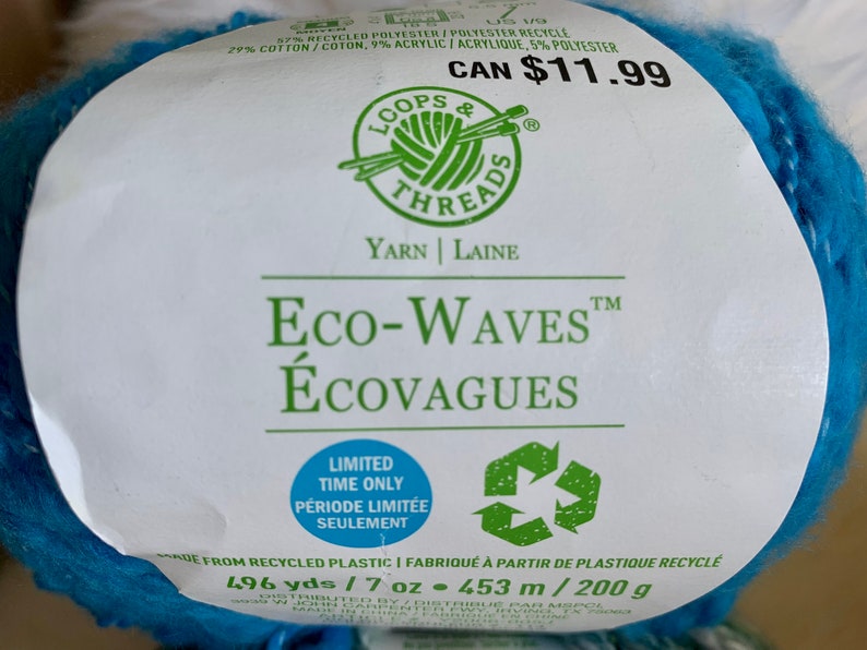 May include: A skein of Loops & Threads Eco-Waves yarn in a bright blue color. The label reads "Eco-Waves &Eacute;covagues" and "Limited Time Only P&eacute;riode Limit&eacute;e Seulement". The yarn is made from recycled plastic and contains 496 yards or 7 ounces (453 meters or 200 grams).