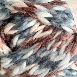 K&ouml;nnte beinhalten: Nahaufnahme eines Kn&auml;uels Garn in einer Farbkombination aus Blau, Wei&szlig; und Rosa. Das Garn ist weich und flauschig mit einer dicken Textur.