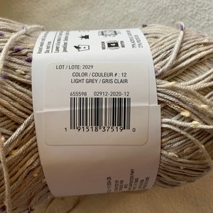 Peut inclure: Une pelote de fil gris clair avec une &eacute;tiquette blanche qui indique "LOT/LOTE: 2029", "COLOR/COULEUR #: 12", "LIGHT GREY/GRIS CLAIR", "655598 02912-2020-12", et un code-barres.