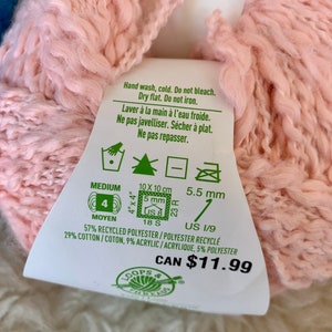 May include: A pink yarn ball with a white label that says "Hand wash, cold. Do not bleach. Dry flat. Do not iron." and "57% Recycled Polyester / Polyester Recycl&eacute; 29% Cotton / Coton, 9% Acrylic /Acrylique, 5% Polyester" and "CAN $11.99".