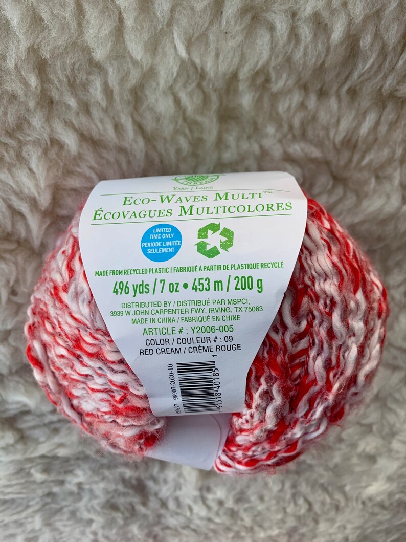May include: A skein of red and cream yarn labeled "Eco-Waves Multi" with the text "496 yds / 7 oz. 453 m / 200 g" and "Color / Couleur # 09 Red Cream / Creme Rouge".
