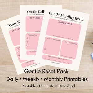 Op de afbeelding: Drie afdrukbare plannerpagina's met roze en witte ontwerpen. De pagina's zijn gelabeld met "Gentle Daily", "Gentle Weekly" en "Gentle Monthly Reset". De tekst "Gentle Reset Pack" en "Daily, Weekly, Monthly Printables" is ook zichtbaar.
