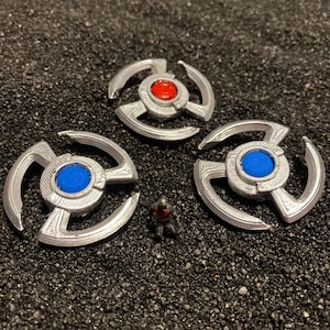 May include: Three silver-colored metal spinners with a blue and red center. The spinners have a starburst design.