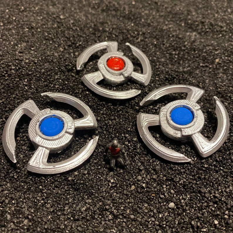 May include: Three silver-colored metal spinners with a blue and red center. The spinners have a starburst design.