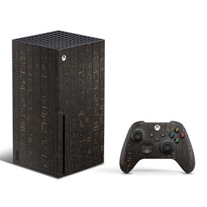 K&ouml;nnte beinhalten: Eine schwarze und goldene Xbox Series X Konsole und ein Controller mit einem Hieroglyphenmuster.