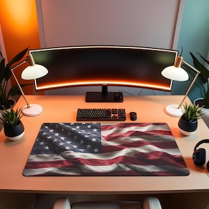 May include: A desk setup featuring a large mousepad with a detailed American flag design. The desk also includes a curved monitor, keyboard, mouse, two desk lamps, and potted plants, creating a modern workspace.