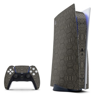 May include: A black and gold PlayStation 5 console with a decorative pattern. The console is standing upright and the front panel is open. A matching black and gold controller is also shown.