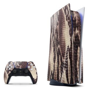 May include: A white and black PlayStation 5 console with a snakeskin pattern. The console is standing upright and the front panel is open. A matching snakeskin pattern controller is shown in front of the console.