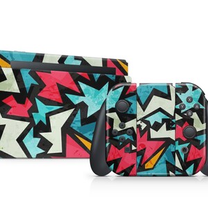 Könnte beinhalten: Ein farbenfrohes Skin-Set für eine Spielekonsole und Controller. Das Design zeigt ein geometrisches Muster aus roten, blauen, weißen und schwarzen Formen. Konsole und Controller sind vor weißem Hintergrund abgebildet.