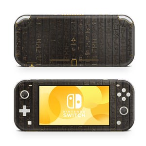 May include: A black and gold Nintendo Switch Lite console with a hieroglyphic design. The console has a black screen with the Nintendo Switch logo and text.