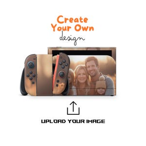 Puede incluir: Una consola de videojuegos personalizada con una foto familiar en la pantalla. Los mandos son marrones y negros. El texto "Create Your Own design" está en naranja, y "UPLOAD YOUR IMAGE" está debajo.