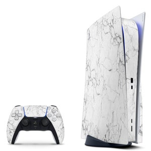 May include: A white PlayStation 5 console with a marble pattern skin. The console is standing upright and has a black base. A white PlayStation 5 controller with a marble pattern skin is also shown.
