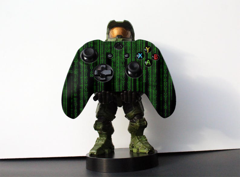 Op de afbeelding: Een groene en zwarte Xbox-controller met een Master Chief-ontwerp. De controller staat op een zwarte basis.