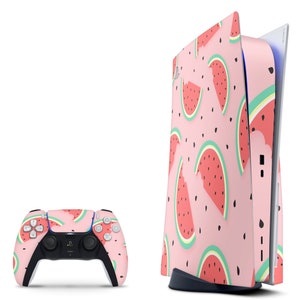 May include: A pink and white PlayStation 5 console with a watermelon pattern. The console is standing upright on a white surface. A matching pink and white PlayStation 5 controller is also shown.