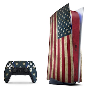 May include: A white and blue PlayStation 5 console with a distressed American flag design. The console is standing upright with the front panel open. A matching controller with a distressed American flag design is shown in front of the console.