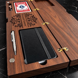 May include: A rectangular dark wood organiser box with gold hinges, featuring a deck of Bicycle playing cards, a silver pen, and a black notebook. The wood surface is laser-engraved with the text Ross and Tammy and decorative scrollwork.