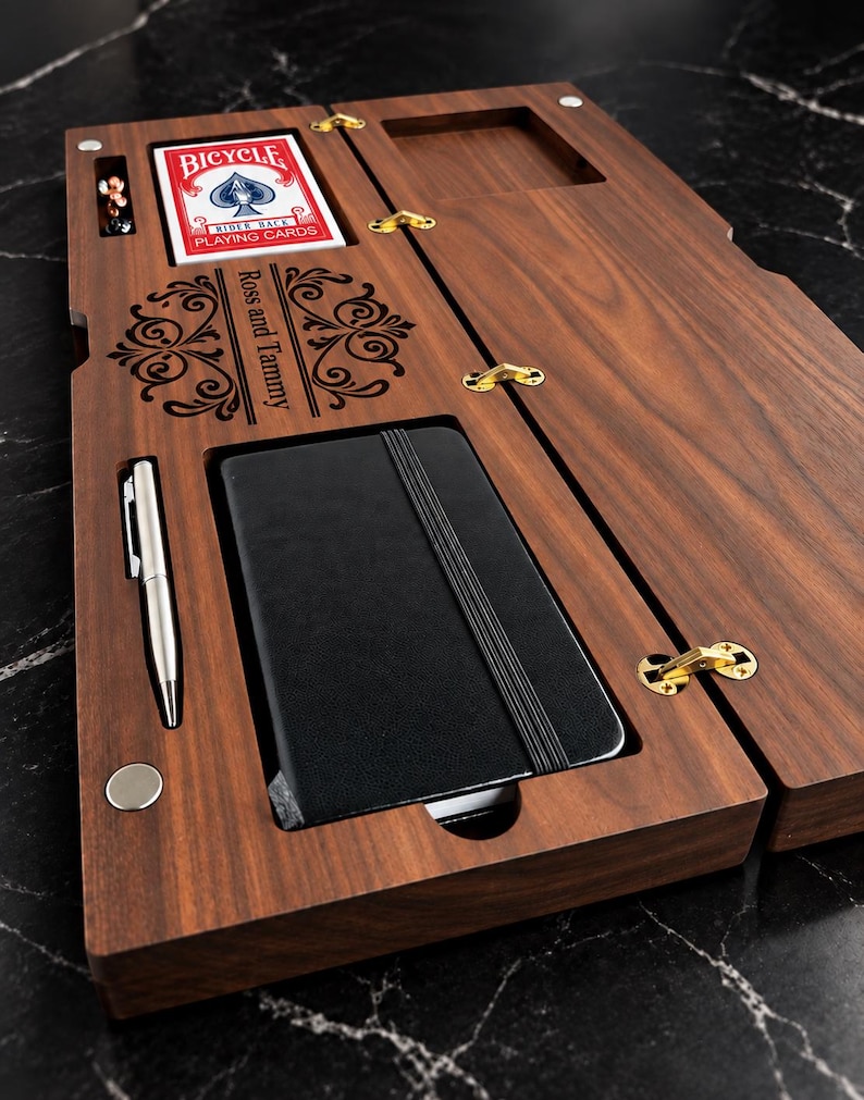 May include: A rectangular dark wood organiser box with gold hinges, featuring a deck of Bicycle playing cards, a silver pen, and a black notebook. The wood surface is laser-engraved with the text Ross and Tammy and decorative scrollwork.