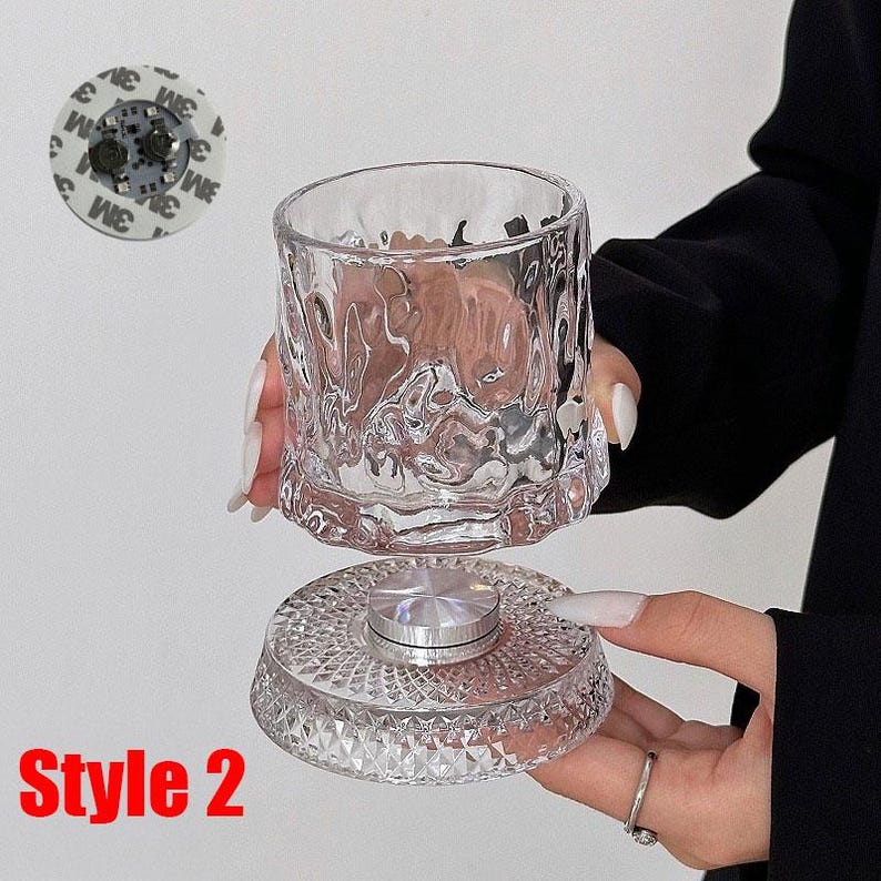 May include: A clear, textured glass cup and base with a silver metal center. The base has a diamond pattern. The text "Style 2" is in red at the bottom. A small, round object with the text "3M" is in the upper left.