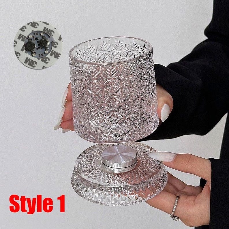 May include: A clear, patterned glass container with a matching base and a silver-colored metal center. The container is held in the air, showcasing its intricate design. The text "Style 1" is visible in the lower left corner.
