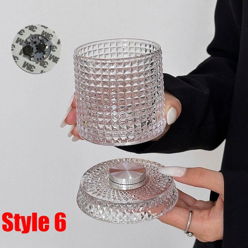 May include: A clear, textured glass container with a matching lid. The container has a diamond pattern, and the lid has a silver center. The text "Style 6" is visible in the lower left corner. A small, round adhesive pad is in the upper left.
