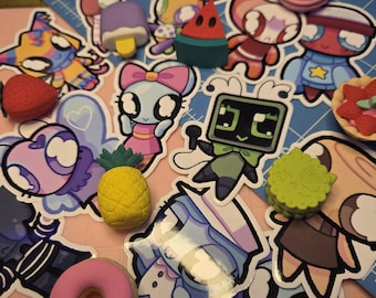 May include: A collection of colorful stickers and erasers featuring various cartoon characters and food items. Includes a yellow pineapple eraser, a pink donut eraser, and several character stickers with vibrant colors.