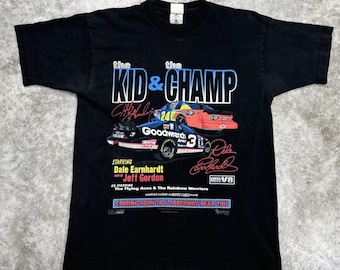 May include: Black t-shirt with a graphic of two race cars, Dale Earnhardt Jr. and Jeff Gordon, with the text "The Kid & Champ" and "Coming Soon to a Speedway Near You".