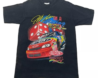 May include: Black t-shirt with a graphic of a red race car with a dice design and the text "We're on a Winning Roll" and "DuPont Refinish Racing".