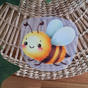 Könnte beinhalten: Eine süße Cartoon-Biene mit einem gelb-schwarz gestreiften Körper, großen blauen Augen und einem fröhlichen Lächeln. Die Biene befindet sich auf einem transparenten Hintergrund.