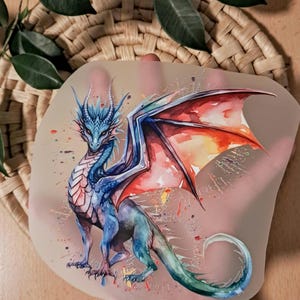 Könnte beinhalten: Aquarell-Illustration eines Drachen in Blau-, Rot- und Grüntönen. Der Drache hat große Flügel und ist vor einem neutralen Hintergrund mit farbigen Farbspritzern platziert. Der Drache ist der Fokus.