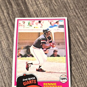 May include: A vintage baseball card featuring Rennie Stennett of the Giants. The card has a pink border and includes the text "2nd Base Giants" and "Topps." Stennett is depicted in his baseball uniform, holding a bat.