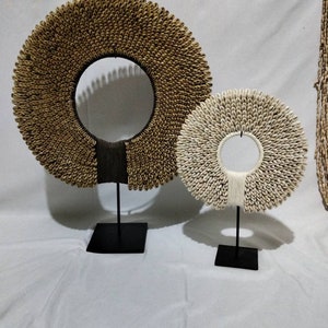 May include: Two Native Borneo Papua necklaces made of shells, one brown and one white, are displayed on black stands against a white background. The text "Native Borneo Papua" is visible at the bottom of the image.