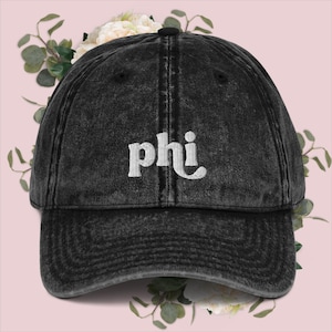 Könnte beinhalten: Eine schwarze, abgenutzte Baseballkappe aus Denim mit weiß gesticktem Text, der "phi" lautet.