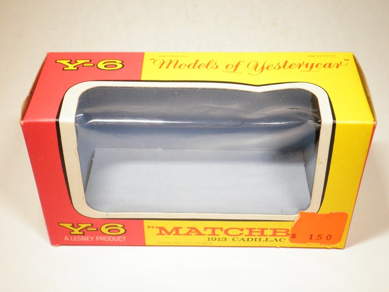 May include: A red and yellow box with a clear plastic window showing the inside. The box is labeled "Y-6" and "Models of Yesteryear" and features a Matchbox 1913 Cadillac toy car. The box also says "A Lesney Product" and "$1.50".