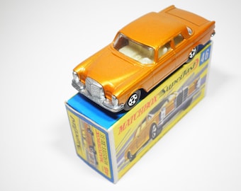 May include: A metallic orange die-cast Mercedes 300 SE toy car with a silver grille and black wheels, resting on its original yellow and blue cardboard box labeled Matchbox Superfast 46 with a graphic illustration of the vehicle.